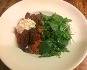 Falafel, aubergine and red pepper harissa casserole with salad.
